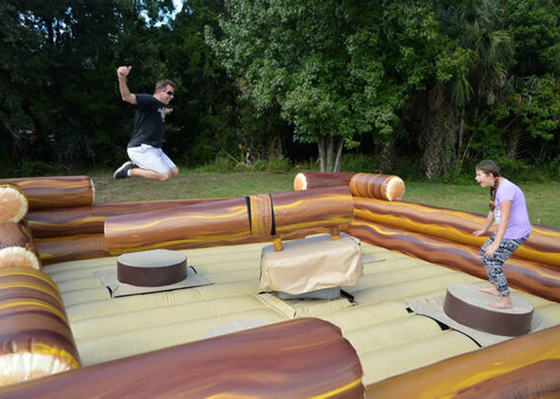 Four players dodging inflatable spinning log arms on the Four Man Log Slammer rental