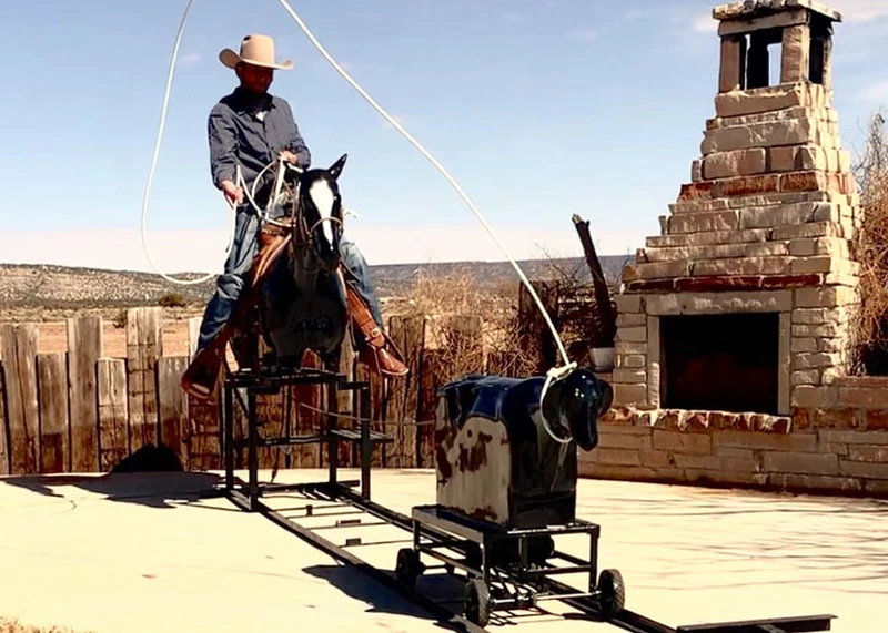 Guest roping a calf from horseback on the Rodeo Roper attraction rental